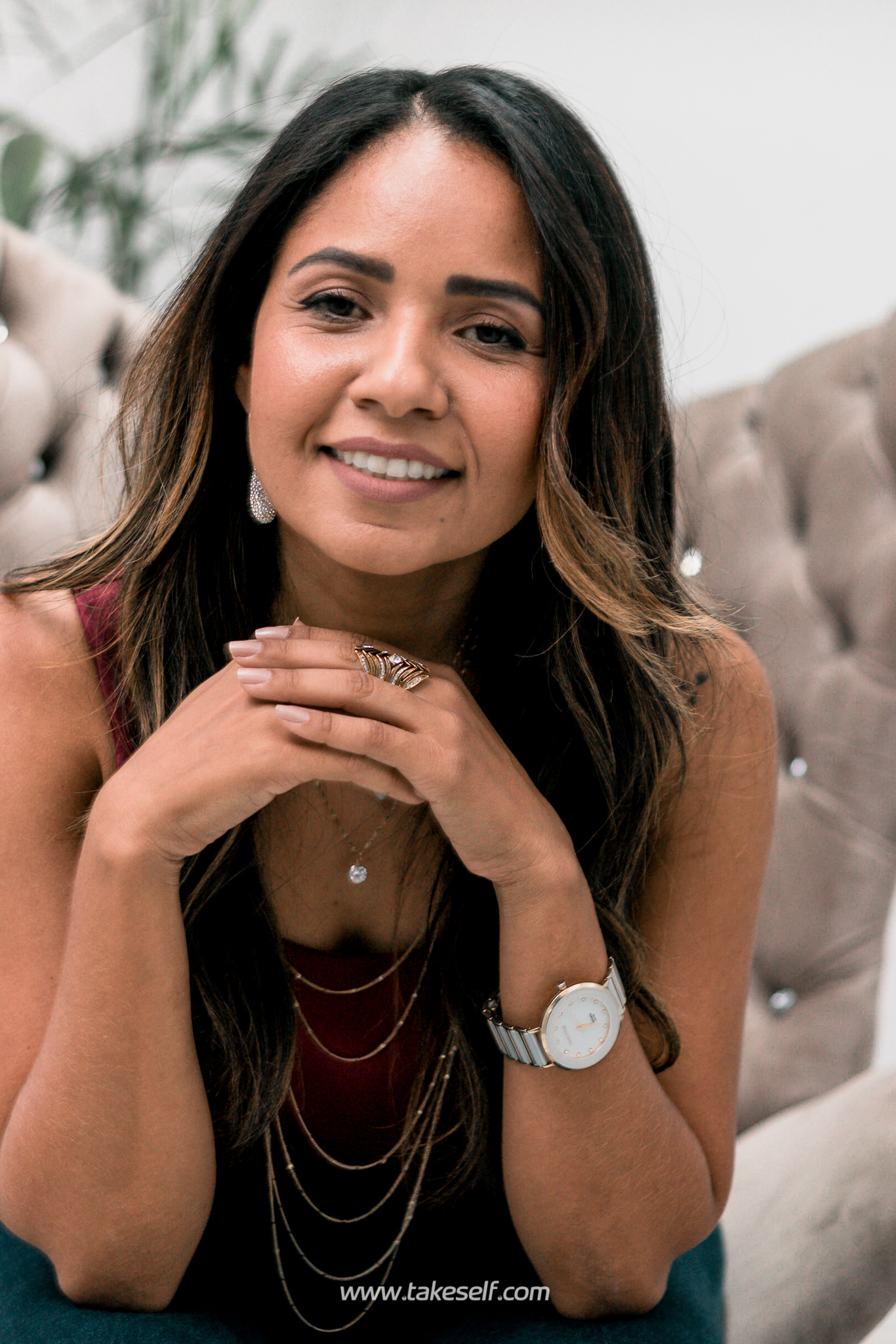 Retrato de uma mulher sorrindo sentada em uma cadeira, usando joias.